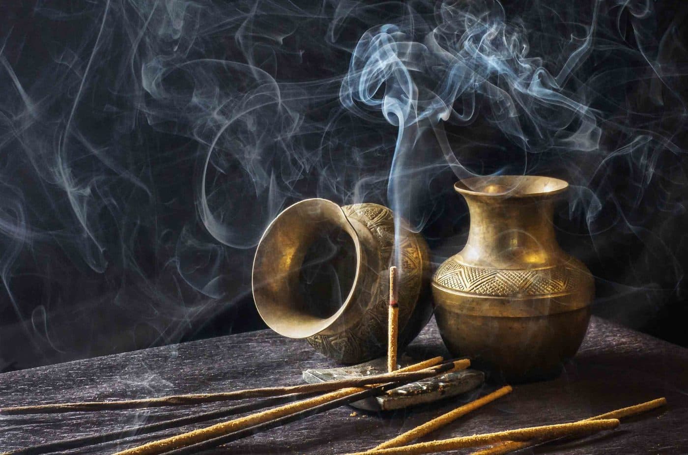 Incense sticks burning beside brass vessels