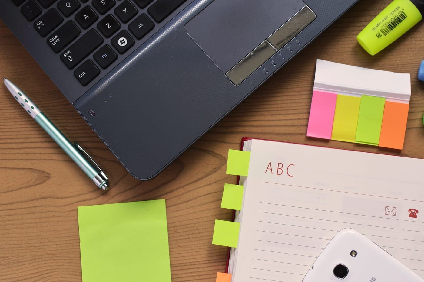 A notebook, pen and sticky notes on a desk